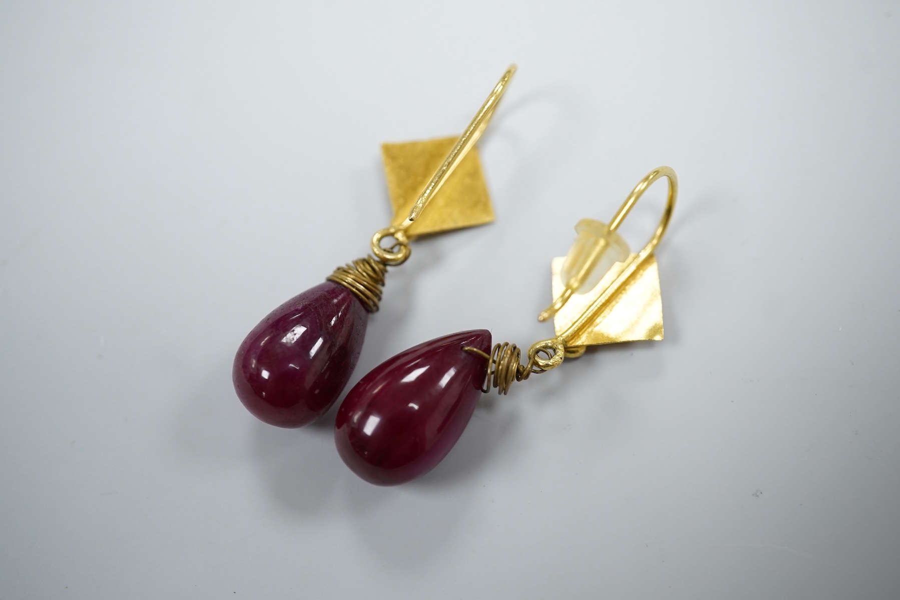 A pair of yellow metal and two stone ruby set teardrop shaped earrings, overall 37mm, gross weight 7.2 grams.